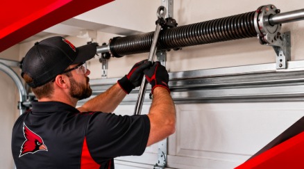 Red Crest technician winding a garage door torsion spring with proper bars